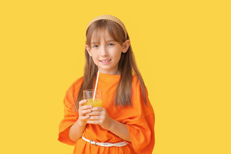 Cute little girl with orange juice on color backgroundの写真素材