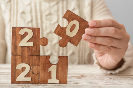 Woman and puzzle pieces with 2021 on table, closeup