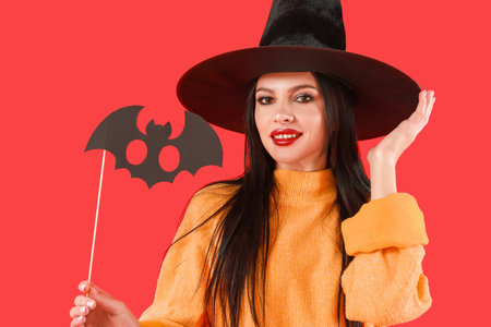 Beautiful young witch with Halloween decor on color backgroundの写真素材