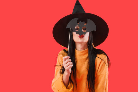 Beautiful young witch with Halloween decor on color backgroundの写真素材