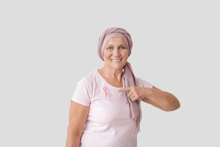 Mature woman after chemotherapy with pink ribbon on light background. breast cancer awarenessの写真素材