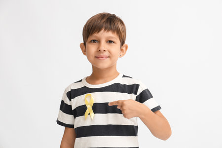 Little boy with golden ribbon on light background. Childhood cancer awareness conceptの写真素材