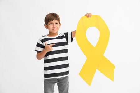 Little boy with golden ribbon on light background. Childhood cancer awareness conceptの写真素材
