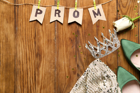 Flags with word PROM, tiara, rose, dress and heels on wooden backgroundの写真素材