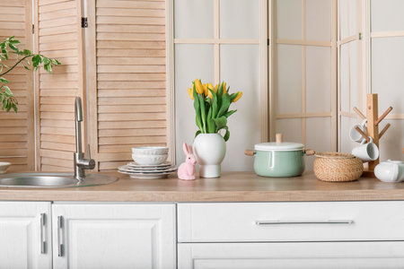 Vase with tulips, Easter rabbit and dishes on counters in kitchenの写真素材
