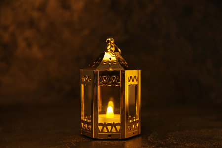 Muslim lantern with glowing candle for Ramadan on dark background