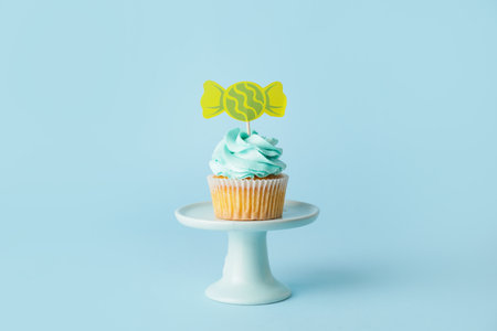 Tasty cupcake with stylish topper on color backgroundの写真素材