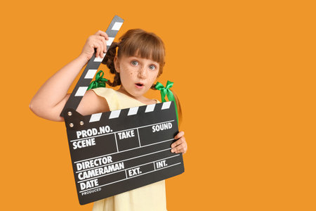 Surprised little girl with movie clapper on color backgroundの写真素材