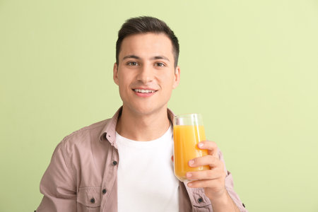 Handsome man with orange juice on color backgroundの写真素材