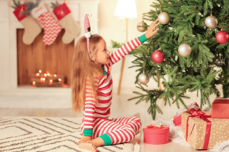 Cute little girl decorating Christmas tree at home