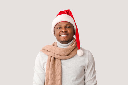 African-American man in Santa hat on light backgroundの写真素材