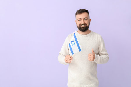 Man with the flag of Israel showing thumb-up on color backgroundの写真素材