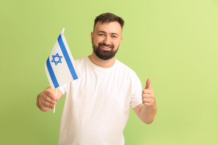Man with the flag of Israel showing thumb-up on color backgroundの写真素材