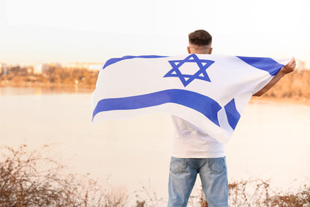 Man with the flag of Israel outdoors, back viewの素材 [FY310198579753]