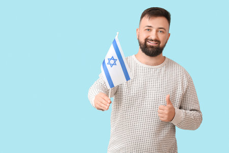 Man with the flag of Israel showing thumb-up on color backgroundの写真素材