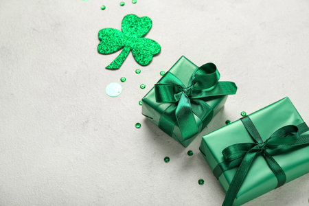 Gifts with sequins and paper clover on white background, closeup. St. Patrick's Day celebration