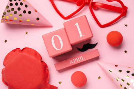 Cube calendar with date 1 APRIL and party decor for Fool's Day celebration on pink background, closeupの写真素材