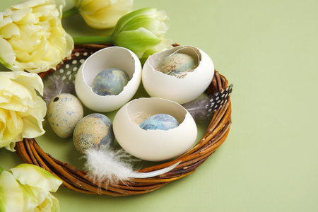 Composition with wreath, Easter eggs and tulip flowers on green background, closeup