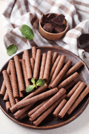 Plate with delicious chocolate wafer rolls on white backgroundの写真素材