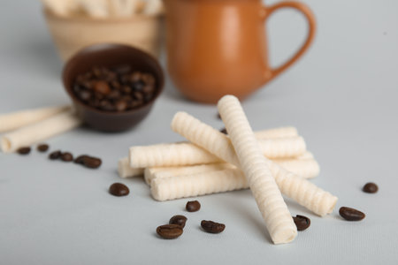 Delicious wafer rolls and coffee beans on gray backgroundの写真素材
