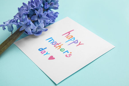 Card with text HAPPY MOTHER'S DAY and hyacinth flower on mint background, closeupの写真素材