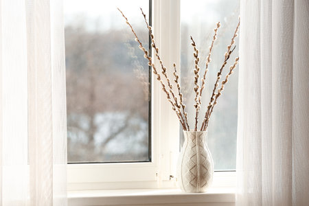 Vase with pussy willow branches on windowsill in roomの写真素材