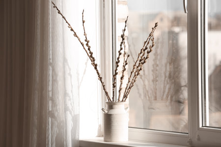 Vase with pussy willow branches on windowsill in roomの写真素材