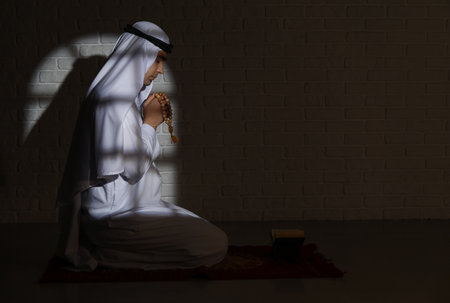 Praying Muslim man in dark roomの写真素材