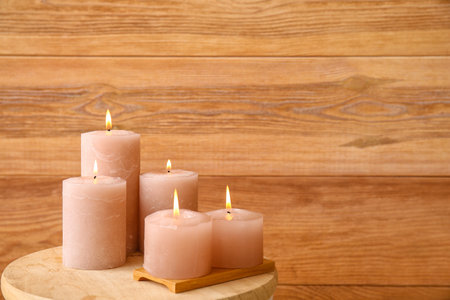 Burning candles on table near wooden wallの写真素材