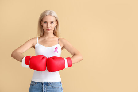 Young woman in boxing gloves on color background. breast cancer awareness conceptの写真素材