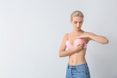 Young woman checking her breast on gray background. cancer awareness conceptの写真素材