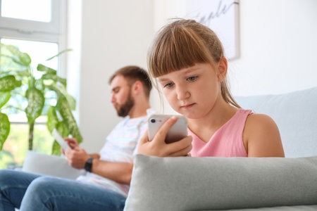 Father and daughter with mobile phone at homeの写真素材