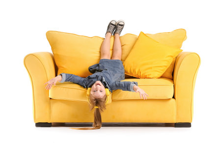 Little girl with headphones on sofa against white backgroundの写真素材