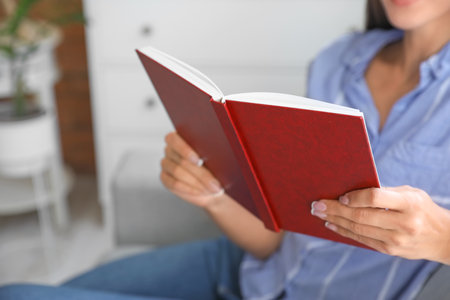 Beautiful young woman reading book at home, closeup