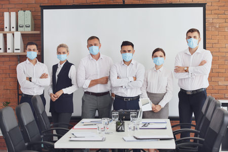 Portrait of business people in medical masks during meeting in officeの写真素材