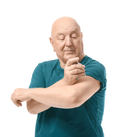 Senior diabetic man giving himself insulin injection on white background