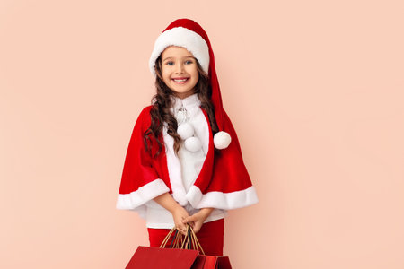 Cute little girl in Santa costume and with shopping bags on color backgroundの写真素材