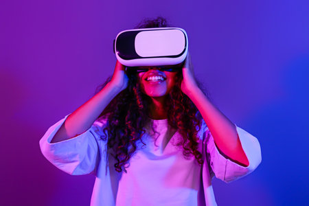 Young woman with virtual reality glasses on dark color background