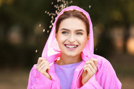Beautiful young woman wearing raincoat outdoors