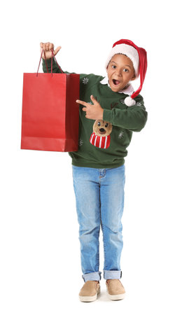 Cute African-American boy in Santa hat and shopping bag on white backgroundの写真素材