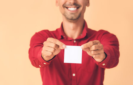 Young man with small blank paper sheet on color backgroundの写真素材