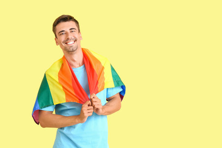 Young man with LGBT flag on color background