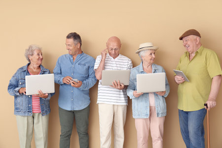 Senior people with different devices near color wall in room