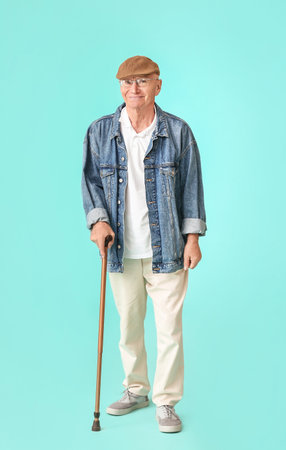 Senior man with walking stick on color backgroundの写真素材