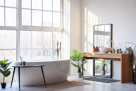Interior of light bathroom with bathtub, table and mirrorの写真素材