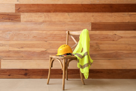 Chair with hardhat and reflective vest near wooden wallの写真素材