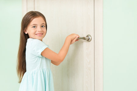 cute little girl opening doorの写真素材