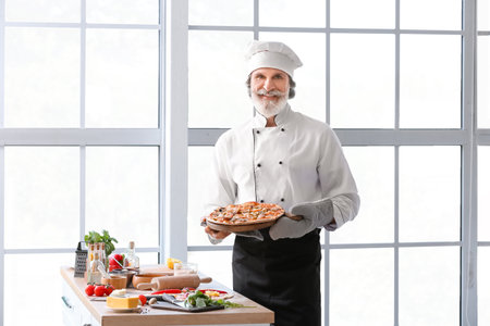 Mature male chef with tasty pizza in the kitchenの写真素材