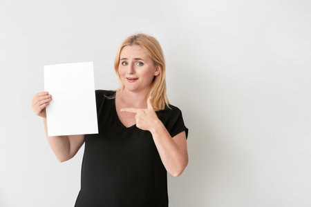 Woman with blank paper sheet on gray backgroundの写真素材