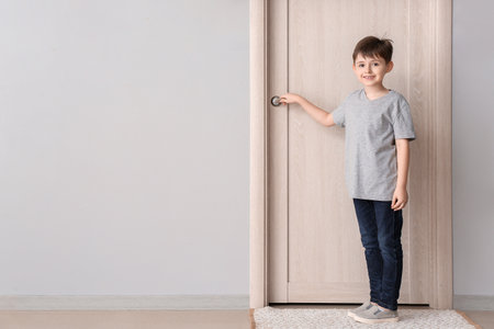Cute little boy standing near closed doorの写真素材